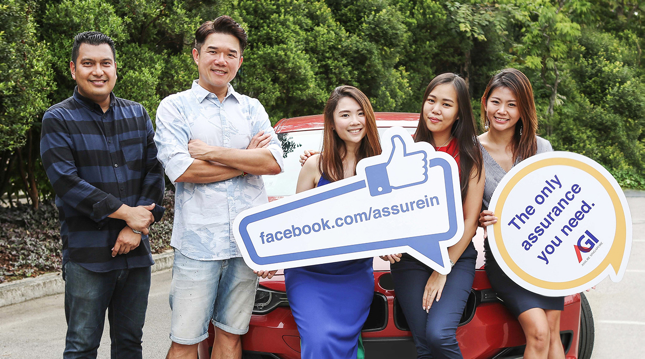 Assure General Insurance team holding branded signs beside a red car